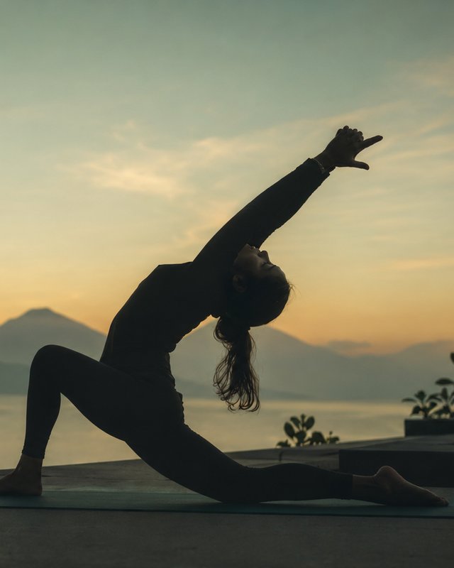 Mujer practicando yoga al amanecer frente al lago y los volcanes