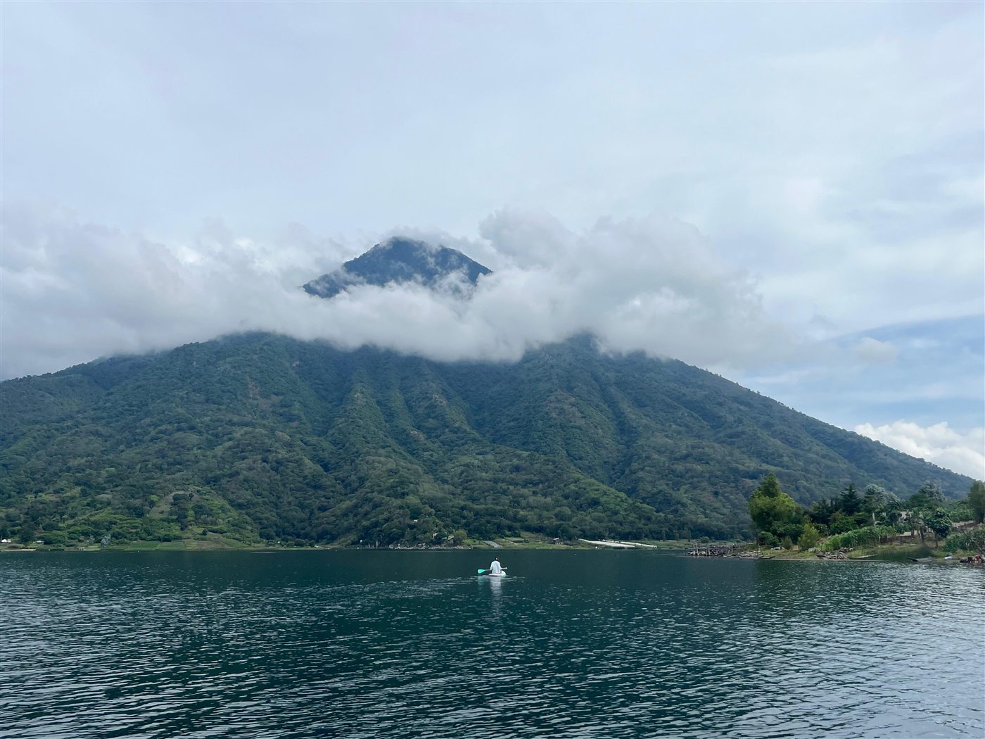 Persona remando en el lago hacia el volcán, avanzando de frente